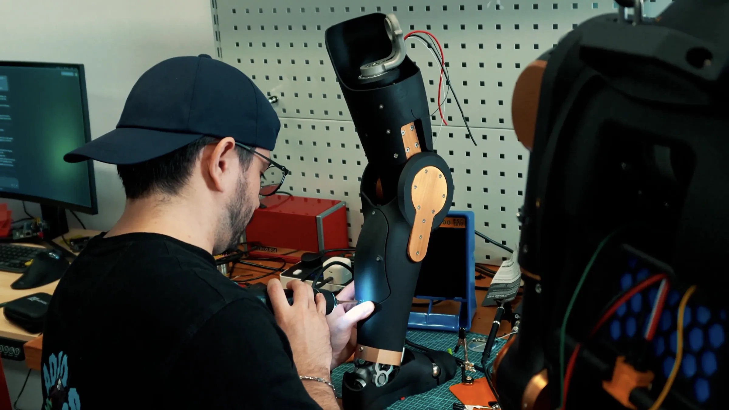 A Menlo engineer assembling an Asimov arm at a workbench